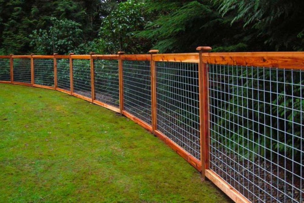 A fence constructed from wire mesh and wooden posts, showcasing a blend of materials for durability and security.